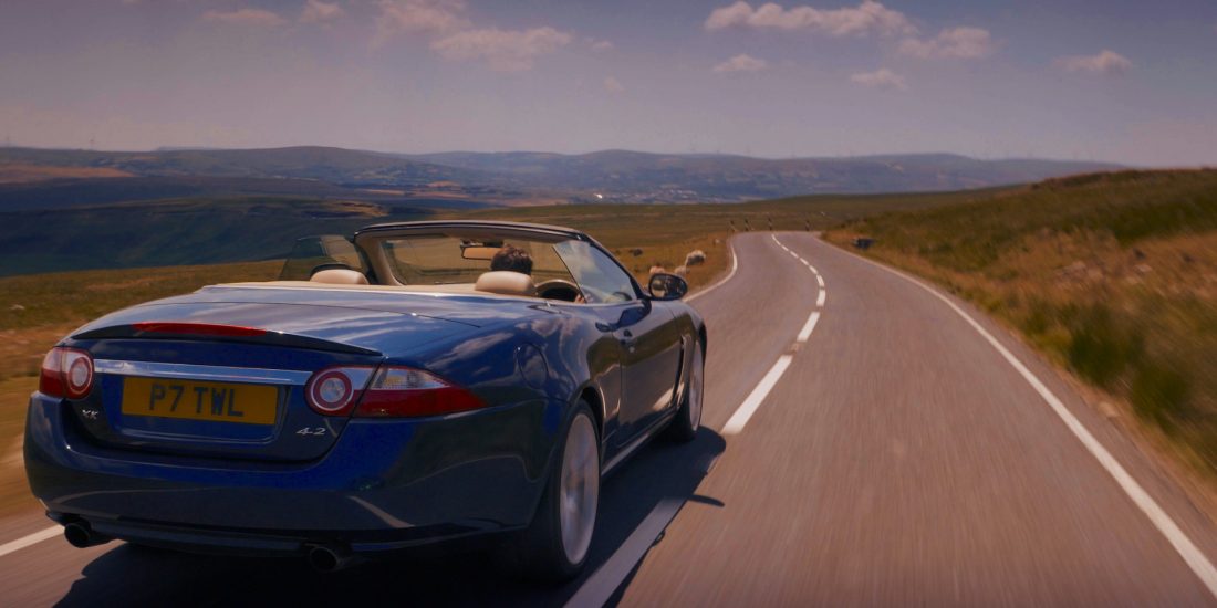 end of an era, last of the v8's, rear view of jaguar sports car on country road